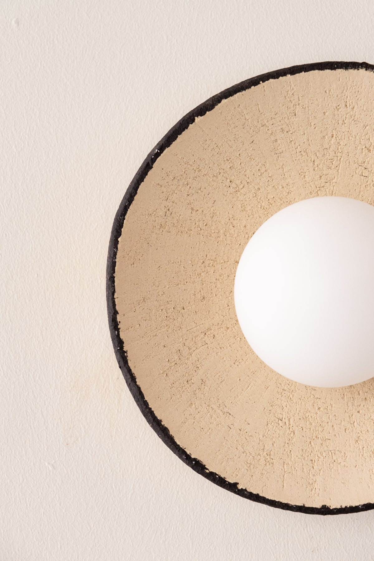 Close-up of the Sahara sand-colored ceramic shade with textured clay surface, black rim and opal globe