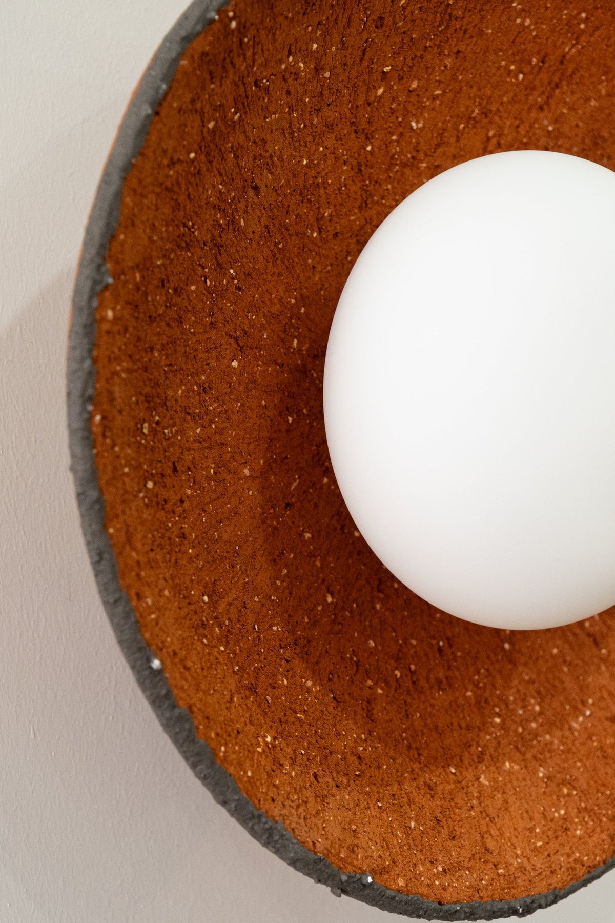 Close-up of the Ember shade showing speckled terracotta clay texture and raw charcoal rim
