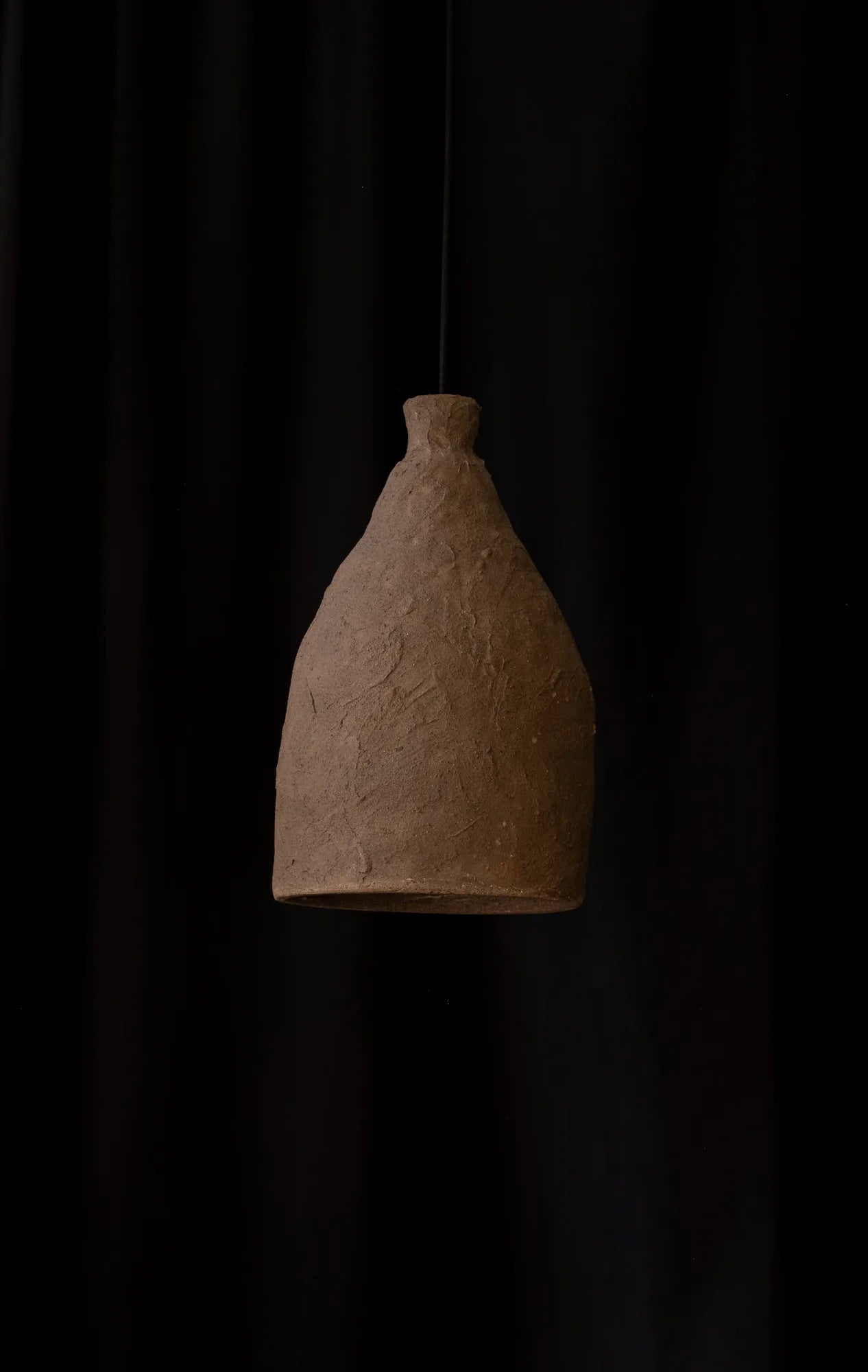 Textured brown stoneware pendant light hanging on a black cord