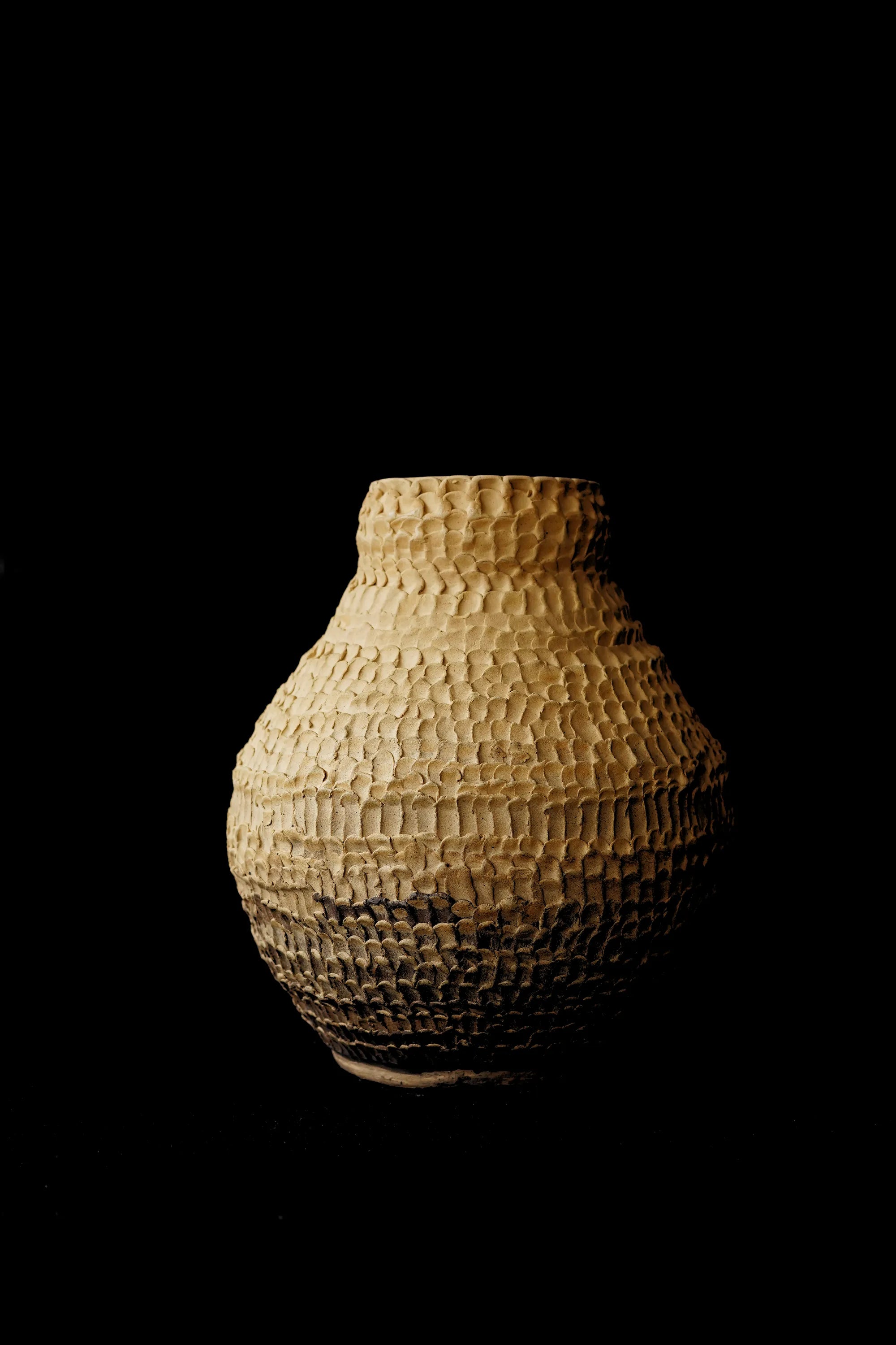 Large hand-built stoneware vase covered in carved scale-like ridges, sand coloured fading to dark brown at the base